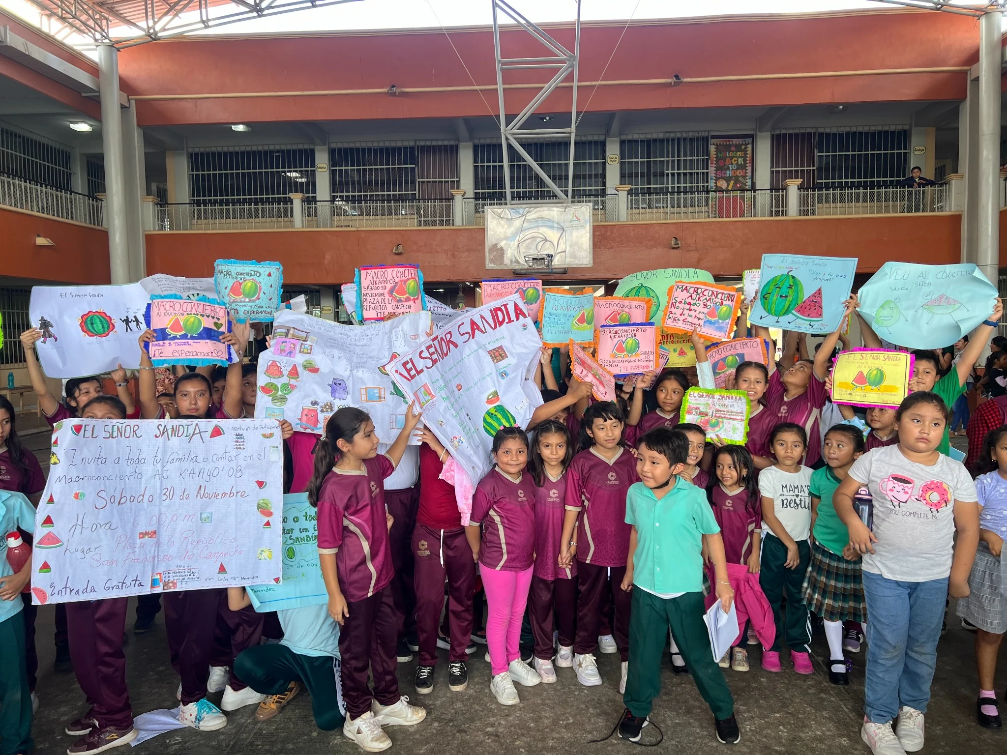 Niñas y niños muestran sus carteles y dibujos del Señor Sandía durante una actividad escolar de CEMIJAZZ.